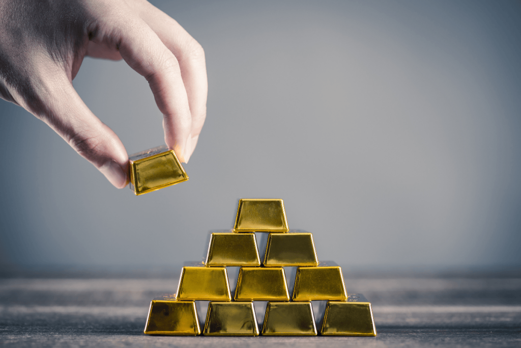 Person stacking gold bars representing investing in gold