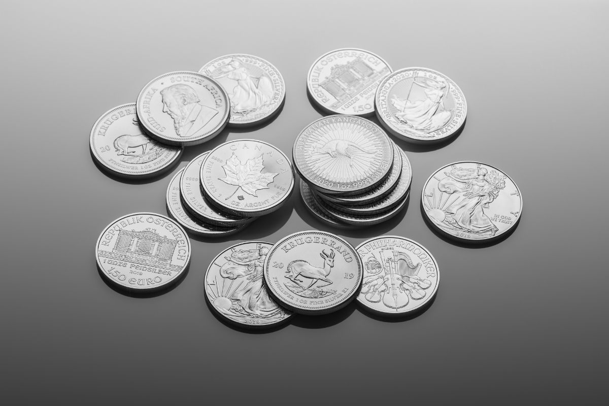 Silver krugerrand, Australian kangaroo, Canadian maple leaf coins laid on table